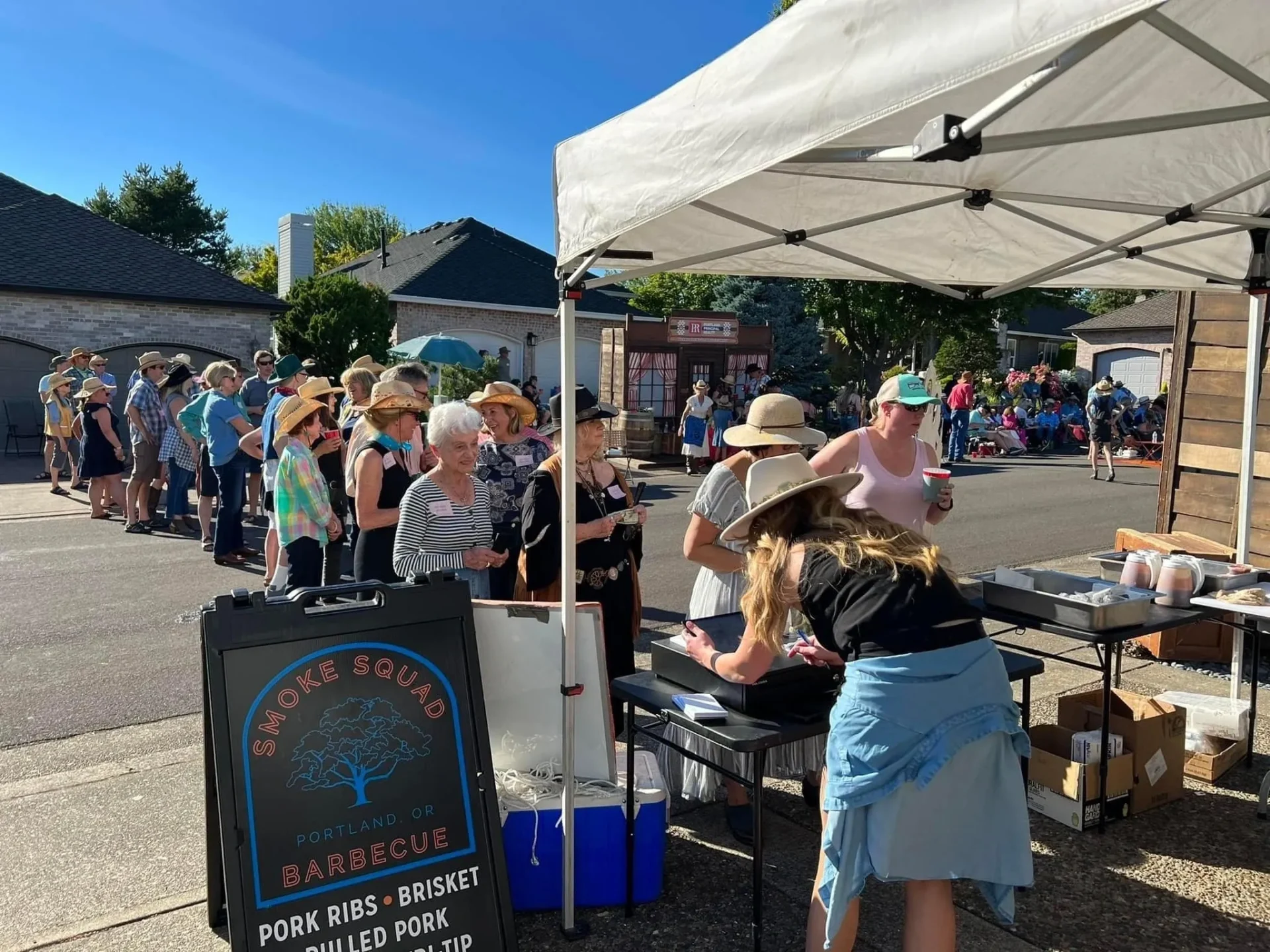 A group of people standing around an outdoor market.