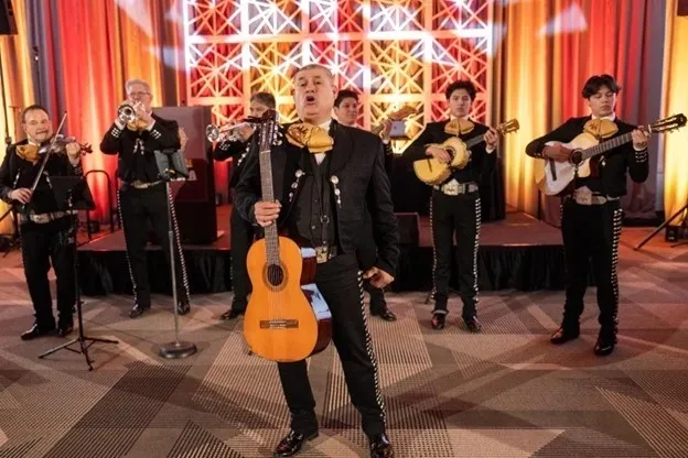 A man in black suit and yellow tie holding a guitar.