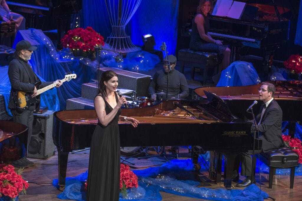 A woman in black dress singing into a microphone.